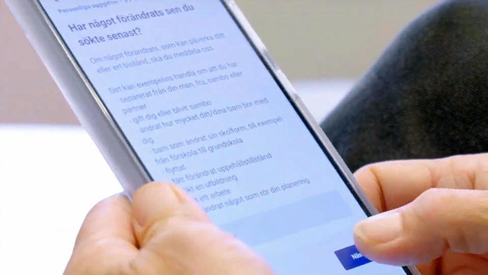 Närbild på en smartphone och tjänsten där man ansöker om ekonomiskt bistånd