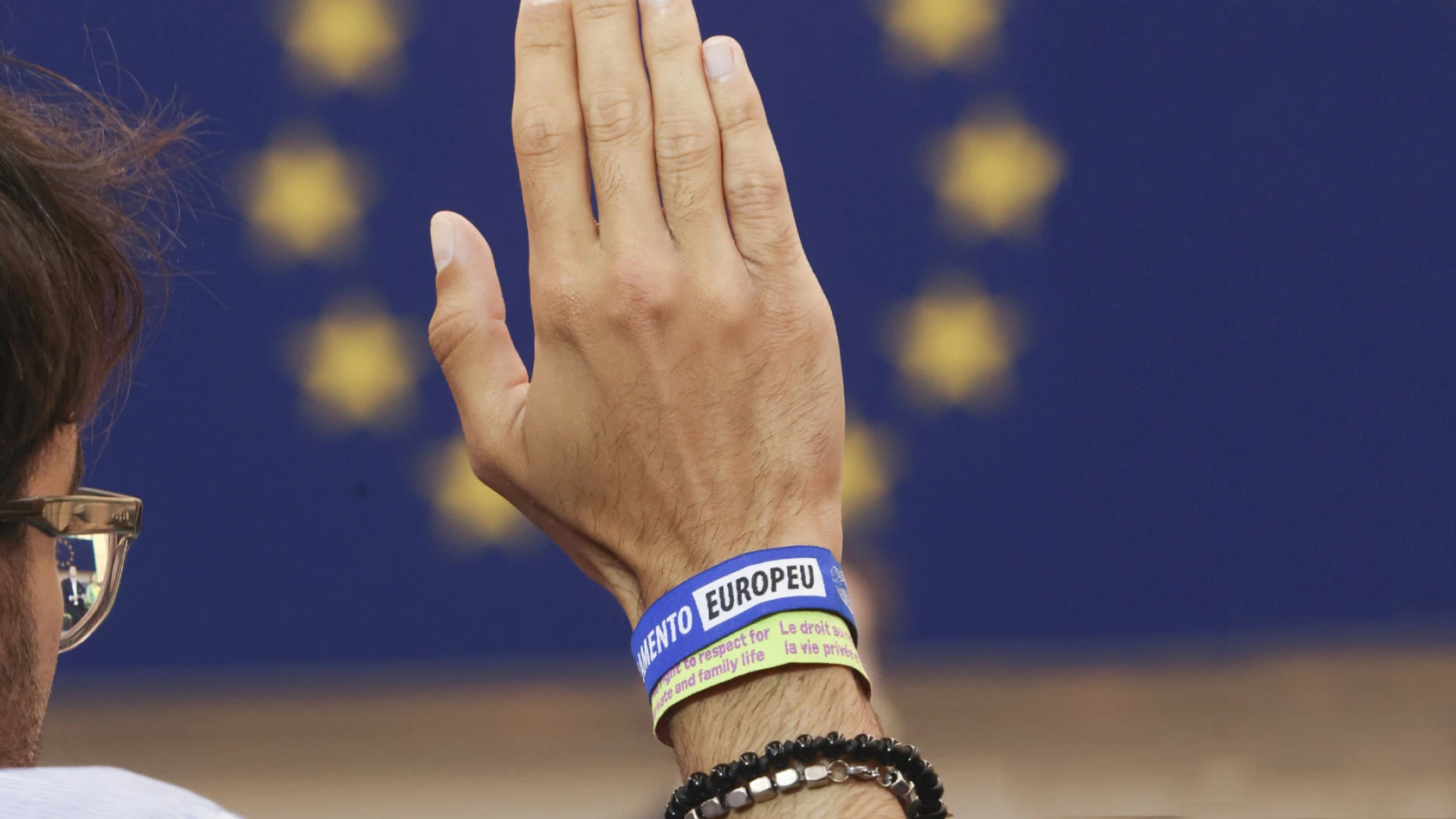 En uppräckt hand med armband med EU-logotyp.