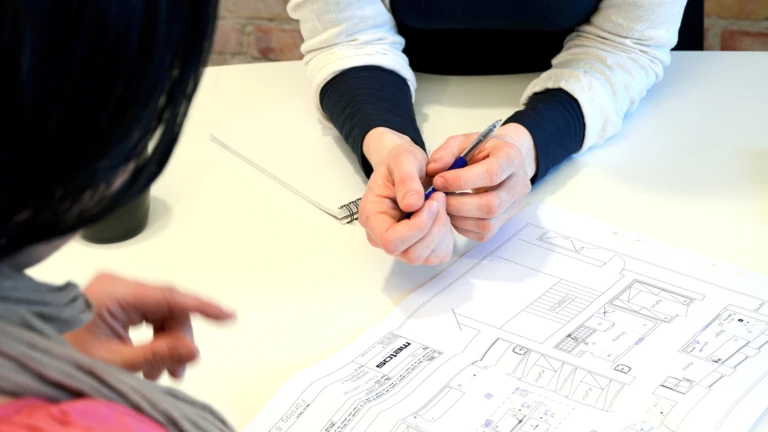 Två personer vid ett bord med en bygglovsritning. (foto: Ida Offenbartl)