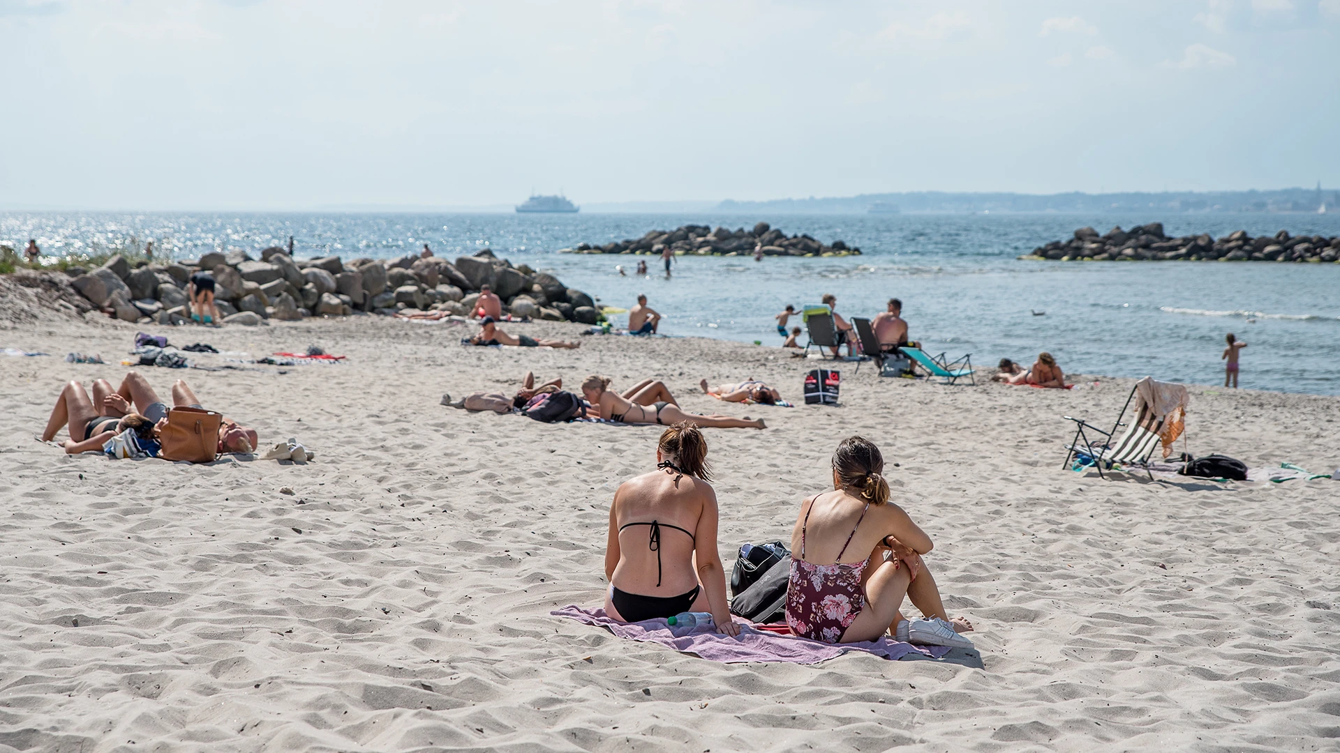 Befolkad strand på Fria bad med Sundet och Danmarksfärja i bakgrunden