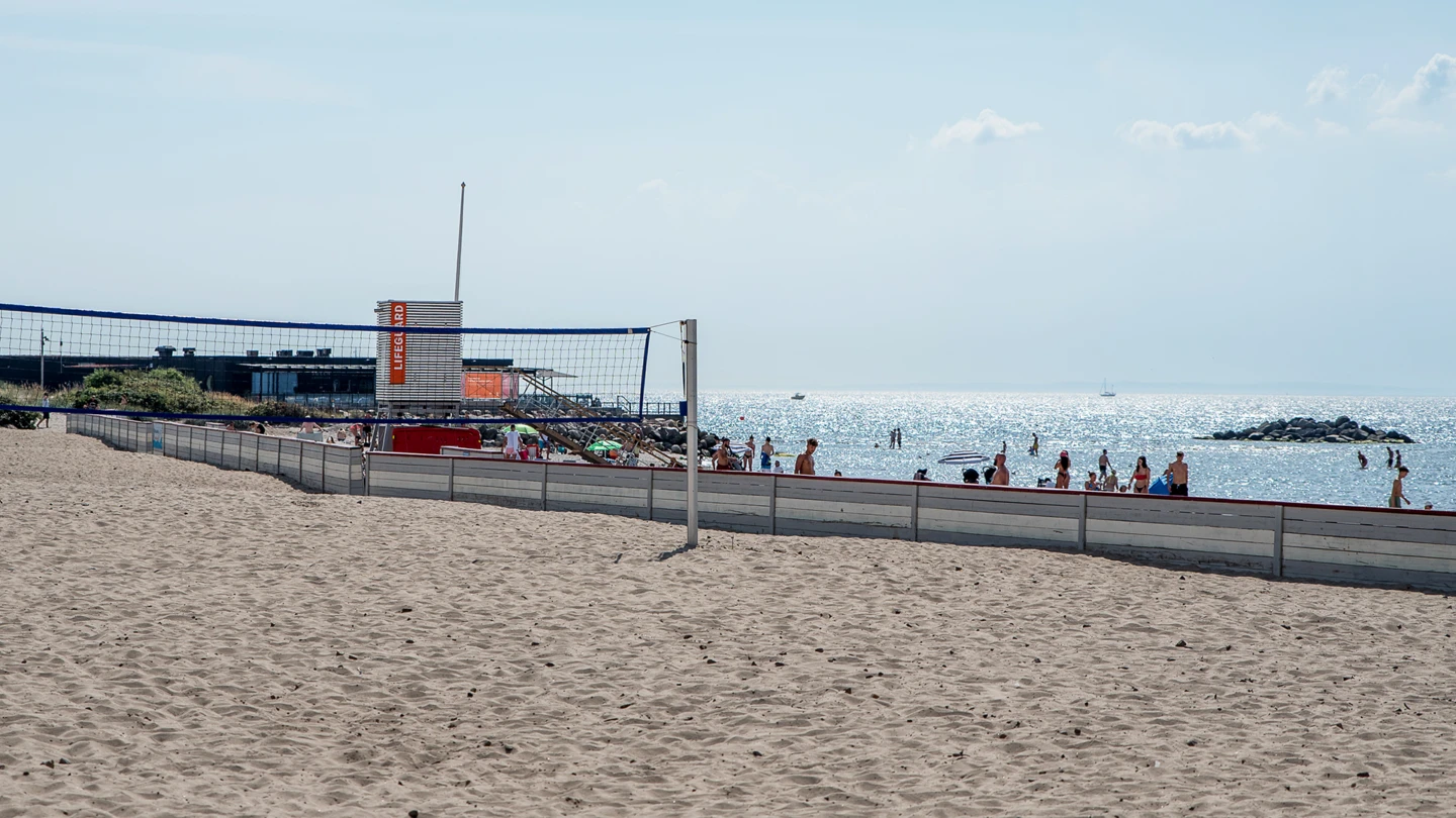 Volleybollnät på Fria bad med havslivräddartorn och strand i bakgrunden.