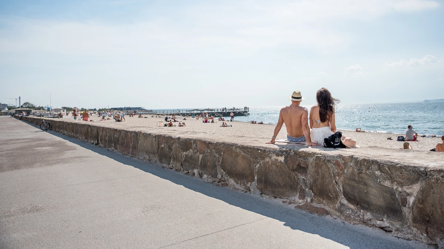 Två personer på muren längs strandpromenaden strax norr om Fria bad i Helsingborg