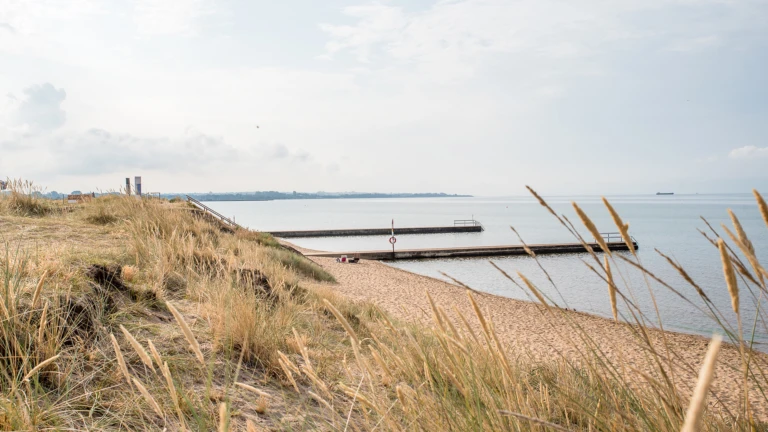 Två bryggor och sandstrand vid Knähakens badplats