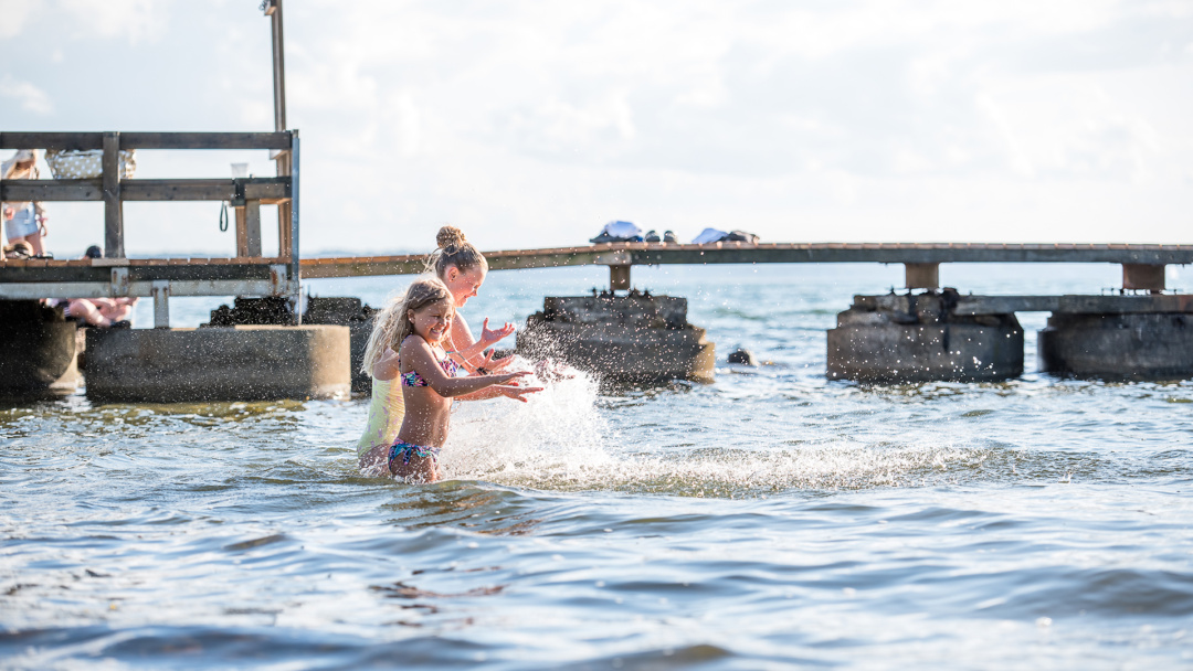 Barn som leker i vattnet vid bryggan vid Larödbaden
