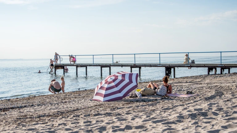 Solbadare på stranden vid Tinkarpsbadet