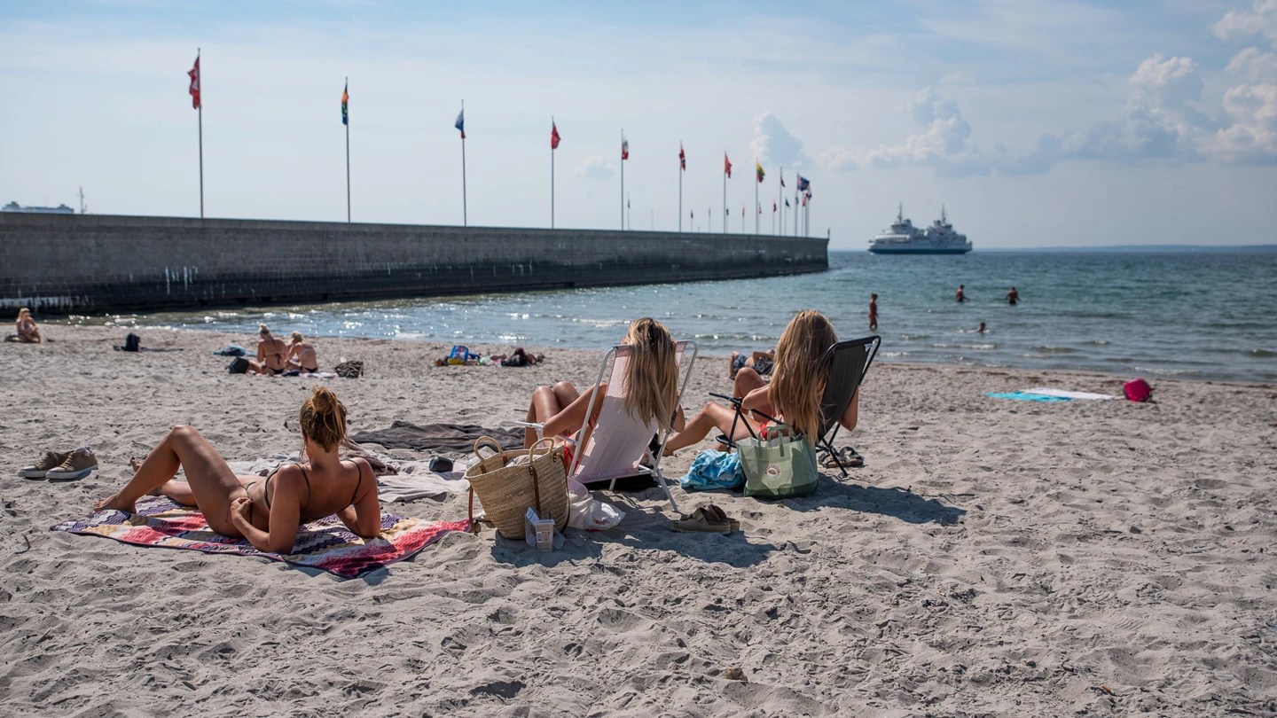 Solbadare på stranden Tropical beach med parapeten och flaggspel i förgrunden