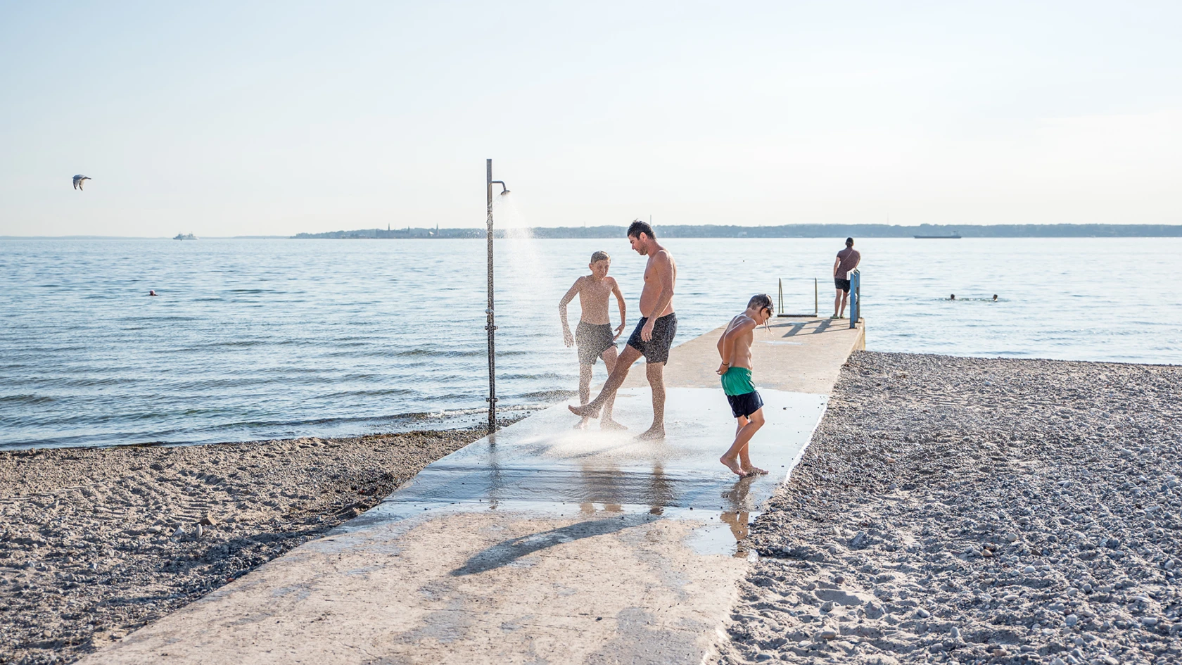 Personer som duschar i uteduschen på bryggan vid Vikingstrand