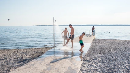 Personer som duschar i uteduschen på bryggan vid Vikingstrand