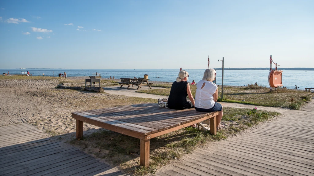 Två personer på bänk vid badplatsen Vikingstrand