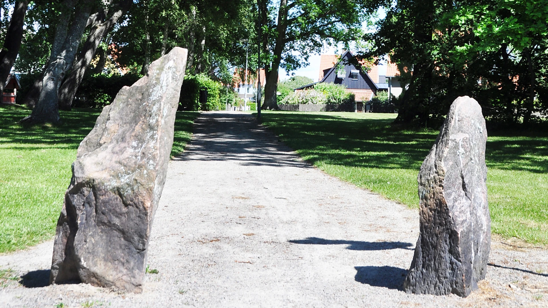 Grusväg genom grönområde i Eskilsminne med två stenar i förgrunden.