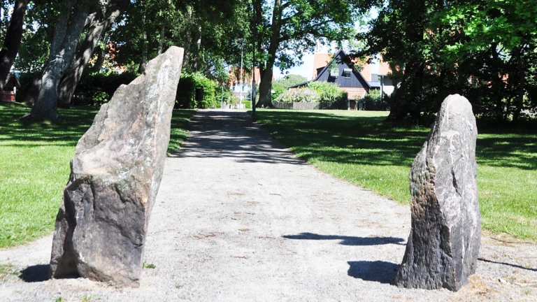 Grusväg genom grönområde i Eskilsminne med två stenar i förgrunden.