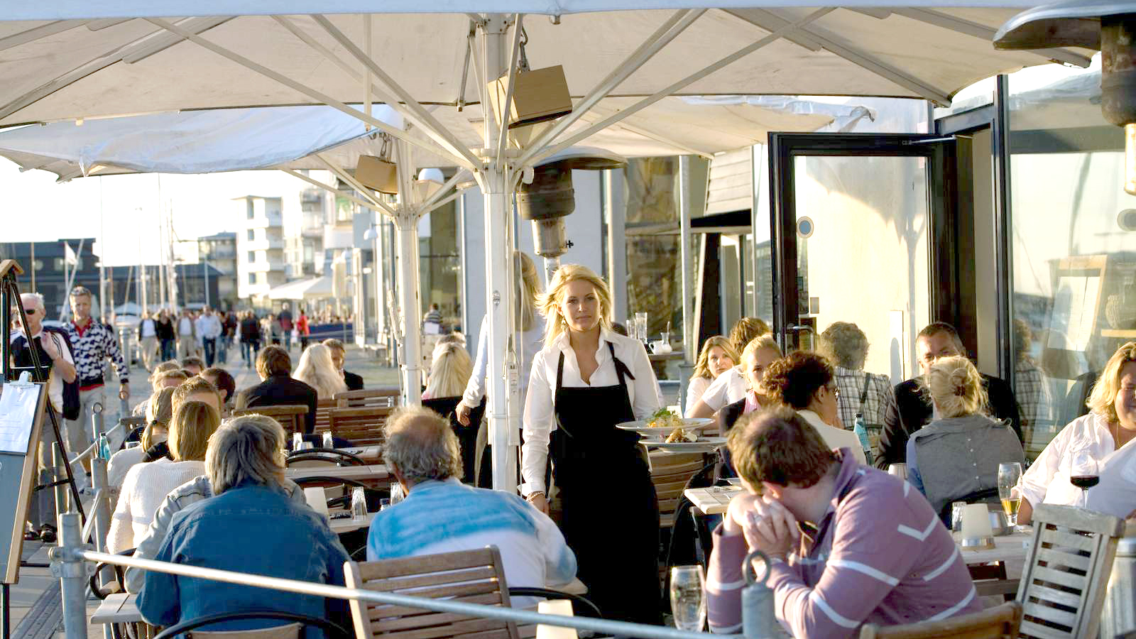 Kvinna serverar mat till kunder på en restaurang i Helsingborg.