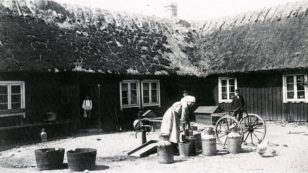 Historisk bild från stadsarkivet: en kvinna bär på hinkar.