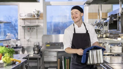 En leende kock arbetar i ett restaurangkök