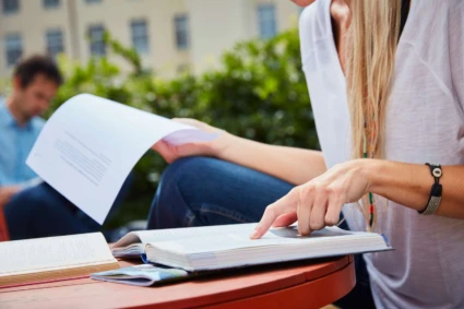 kvinna vid ett bord som pekar i en bok.