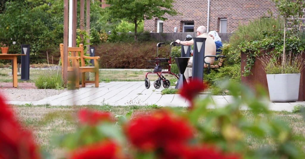 Ett äldre par som sitter på en bänk i en trädgård.