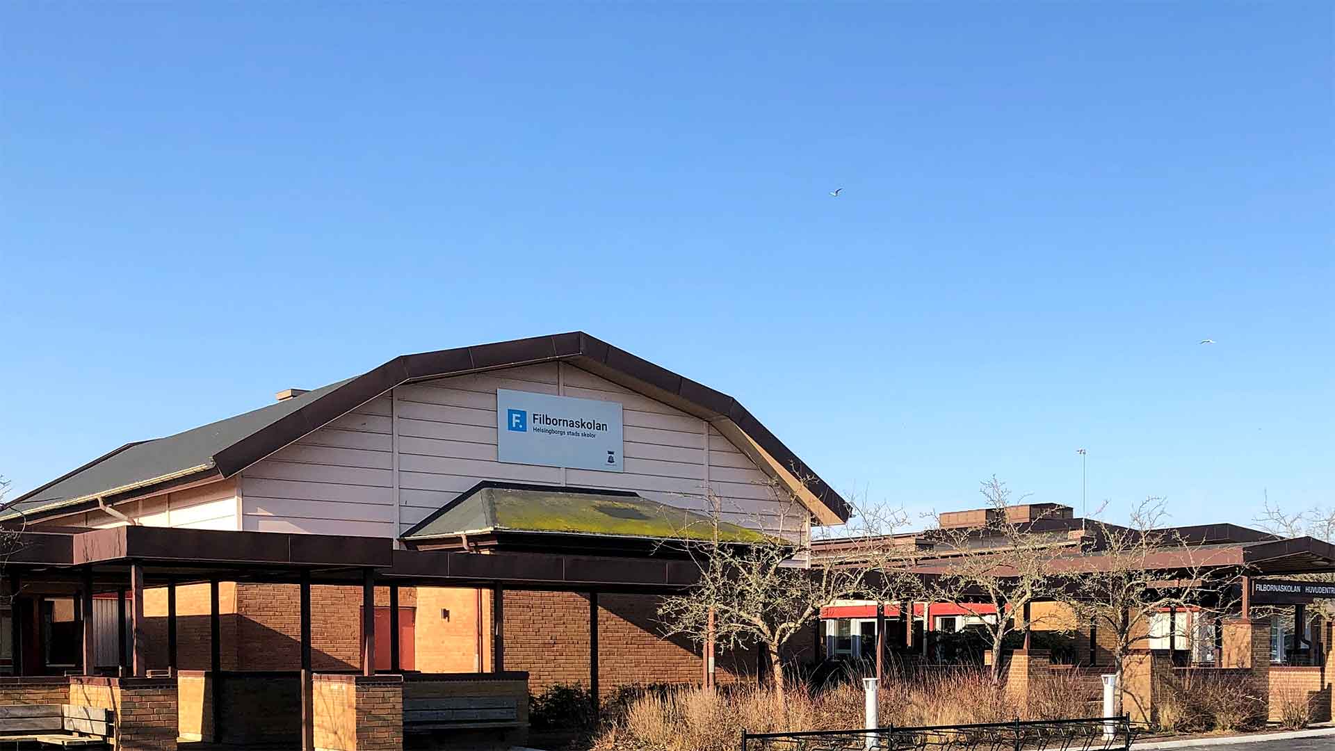 Foto på Filbornaskolans skolbyggnad, entrén mot blå himmel