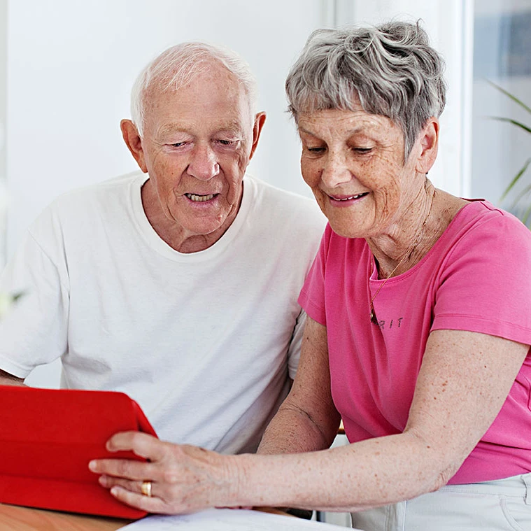 Ett äldre par sitter och tittar på en surfplatta.