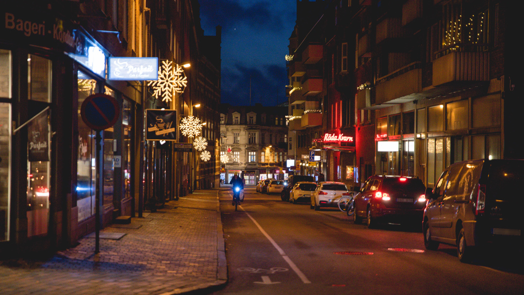 Gata i Helsingborg med juldekorationer, en cyklist och parkerade bilar.