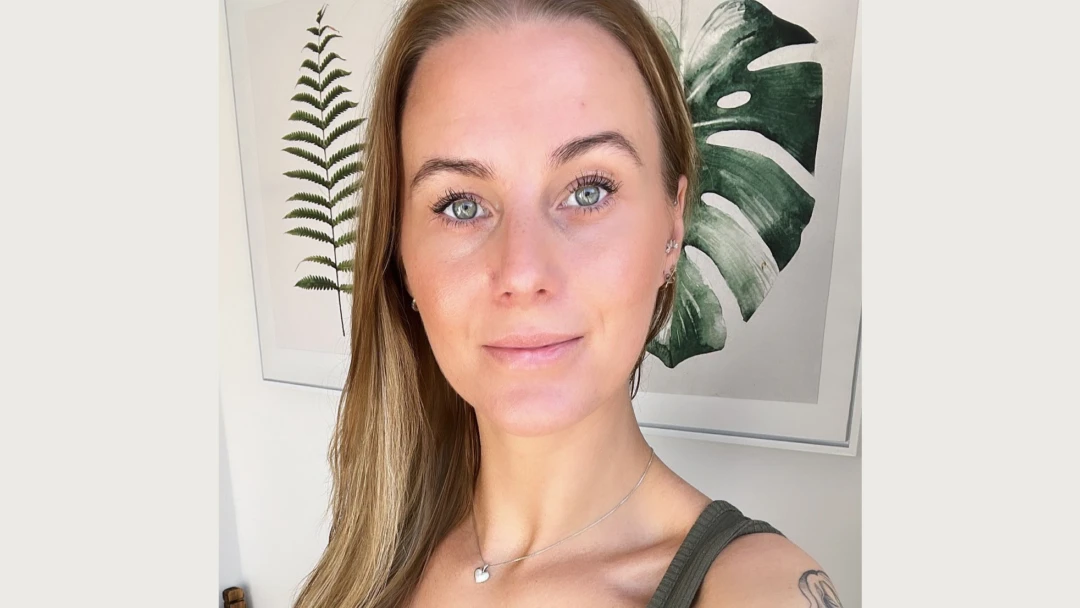 Kvinna med brunt hår står framför en tavla