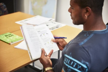 En man som sitter vid ett bord och läser en bok