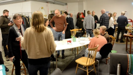 En grupp männikskor står och pratar runt ett vitt bord under en klimat_AW med Helsingborgarnas klimatavtal.