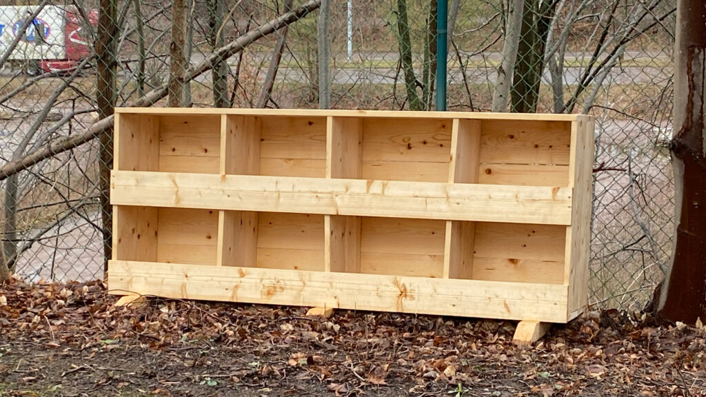 En trämöbel med åtta olika fack som står ute i en trädgård.