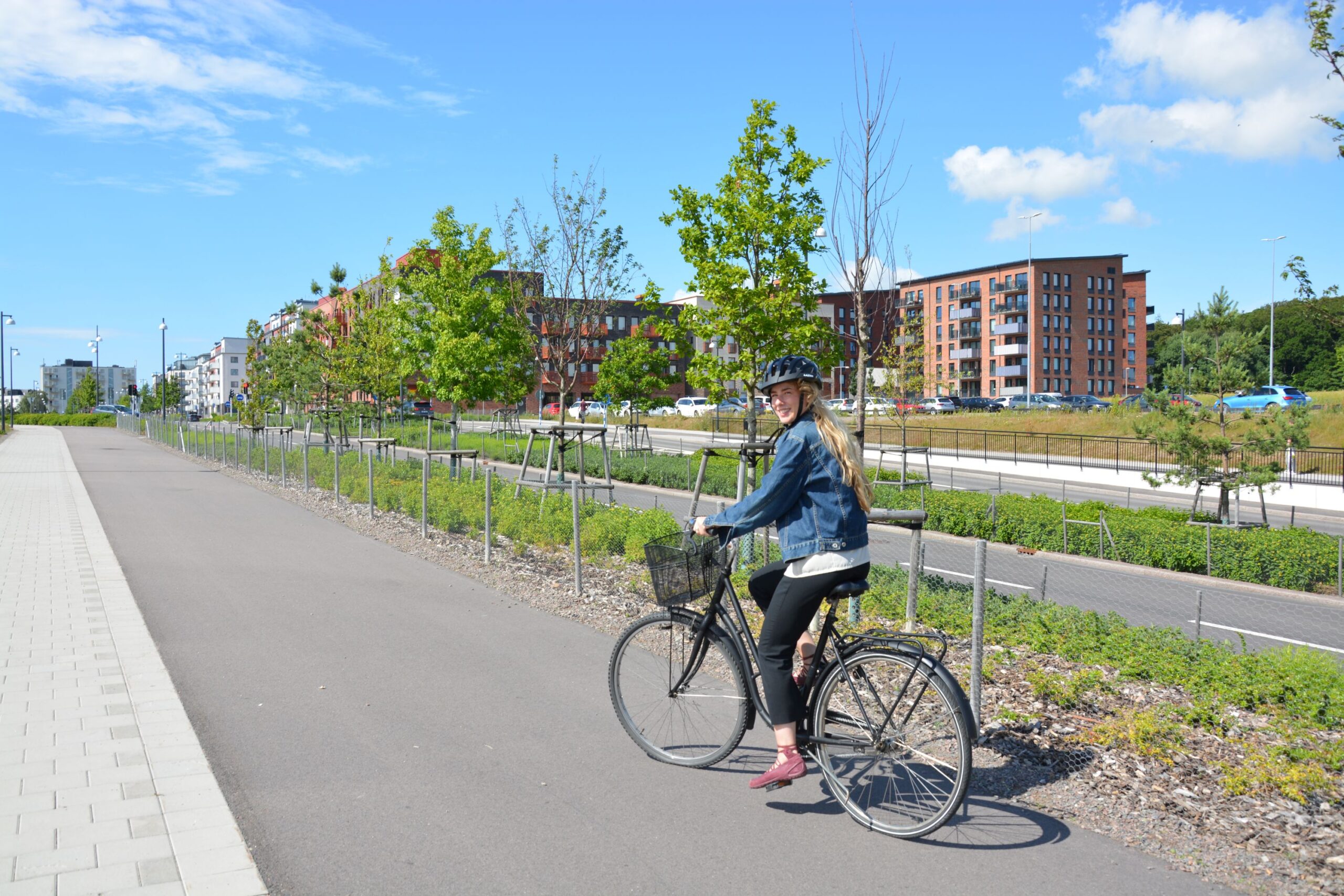 Kvinna cyklar på cykelväg och bostadshus i Mariastaden syns i bakgrunden.
