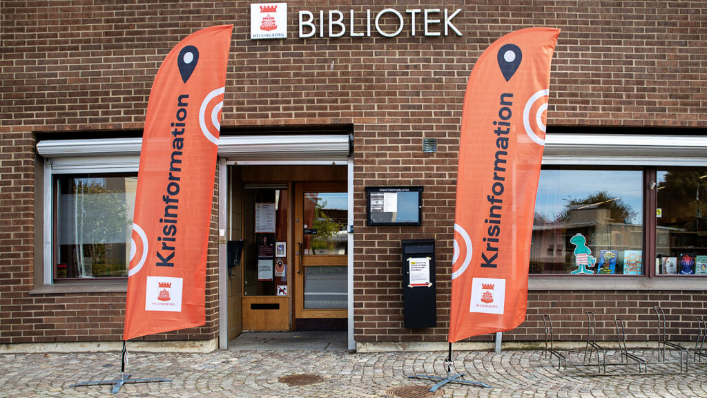 Två flaggskyltar med texten "Krisinformation" utanför entrén till ett av stadens bibliotek