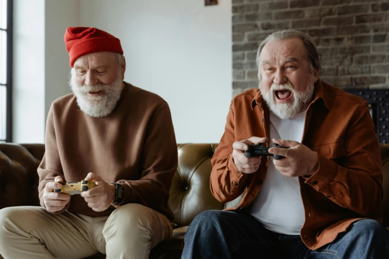 Två äldre män med skägg spelar tv-spel engagerat.