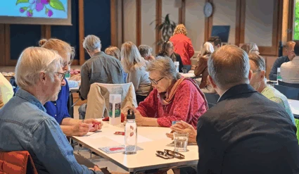 Fem personer runt ett bord som samtalar.