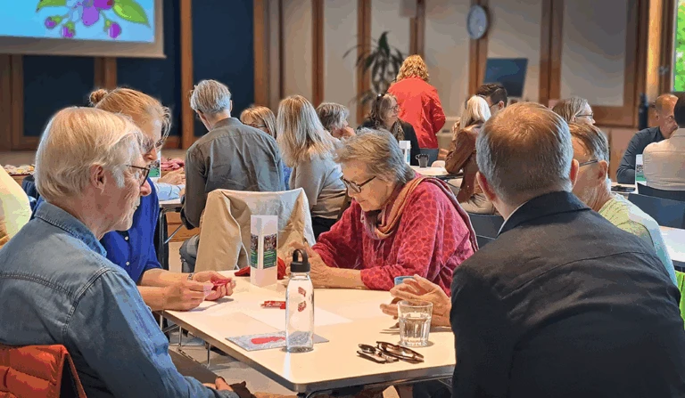 Fem personer runt ett bord som samtalar.