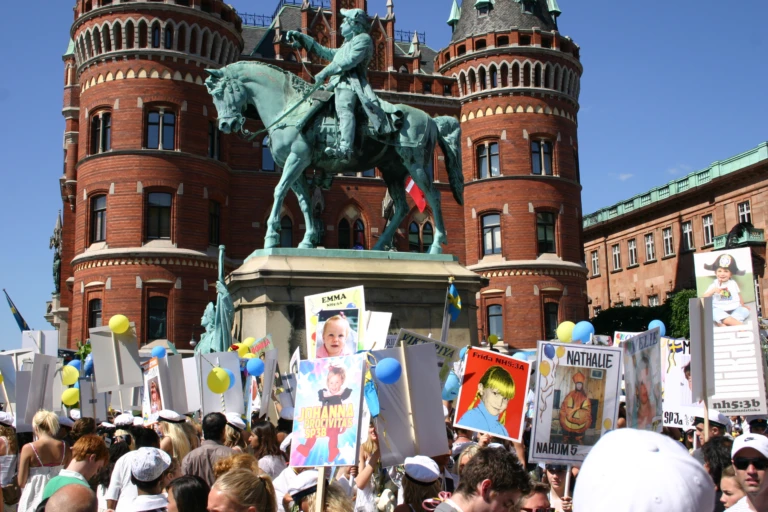 Studenter med studentplakat nedanför Magnus Stenbock-statyn framför Rådhuset