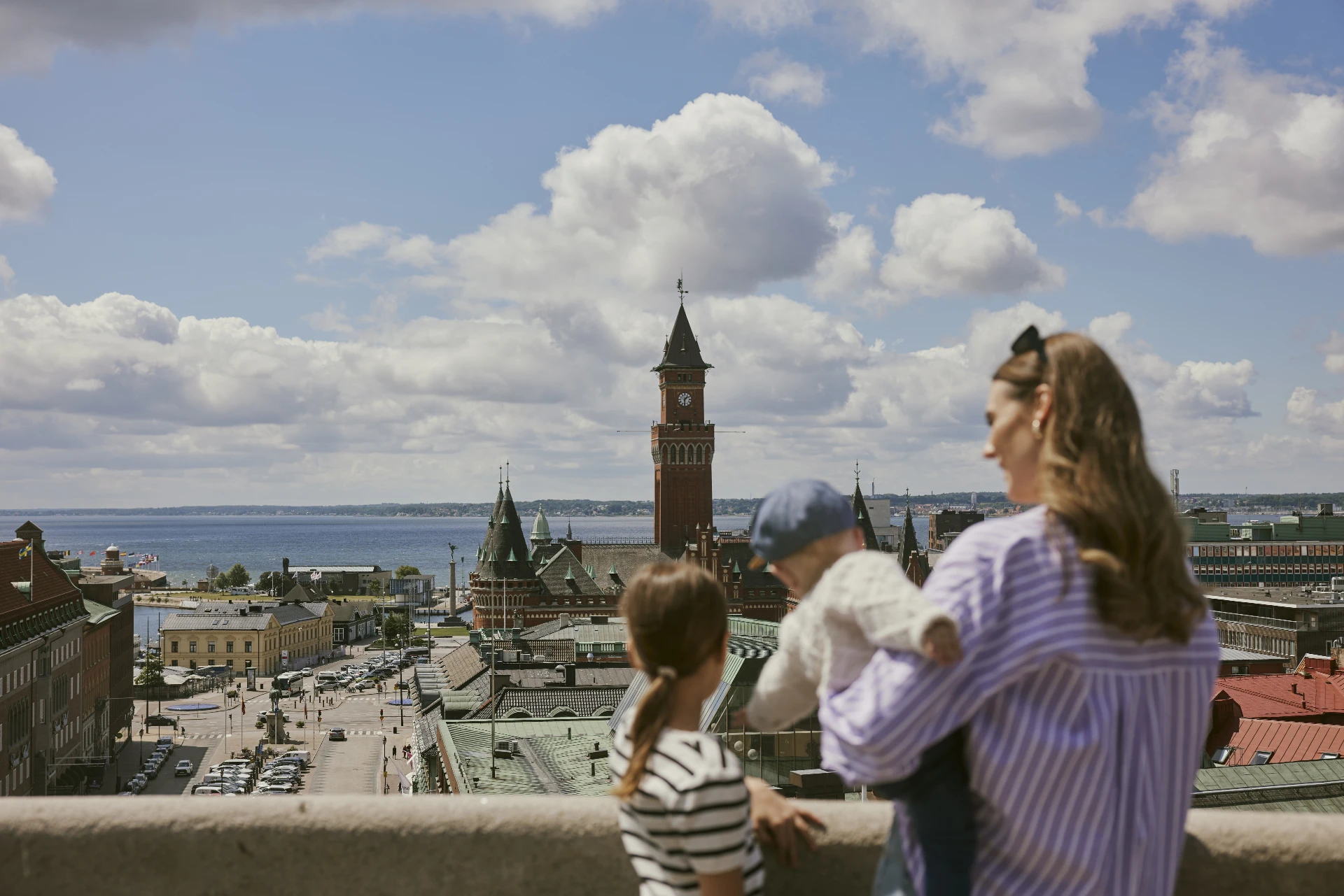 En kvinna och två barn tittar ut över Stortorget och Rådhuset från Terrasstrappornas topp