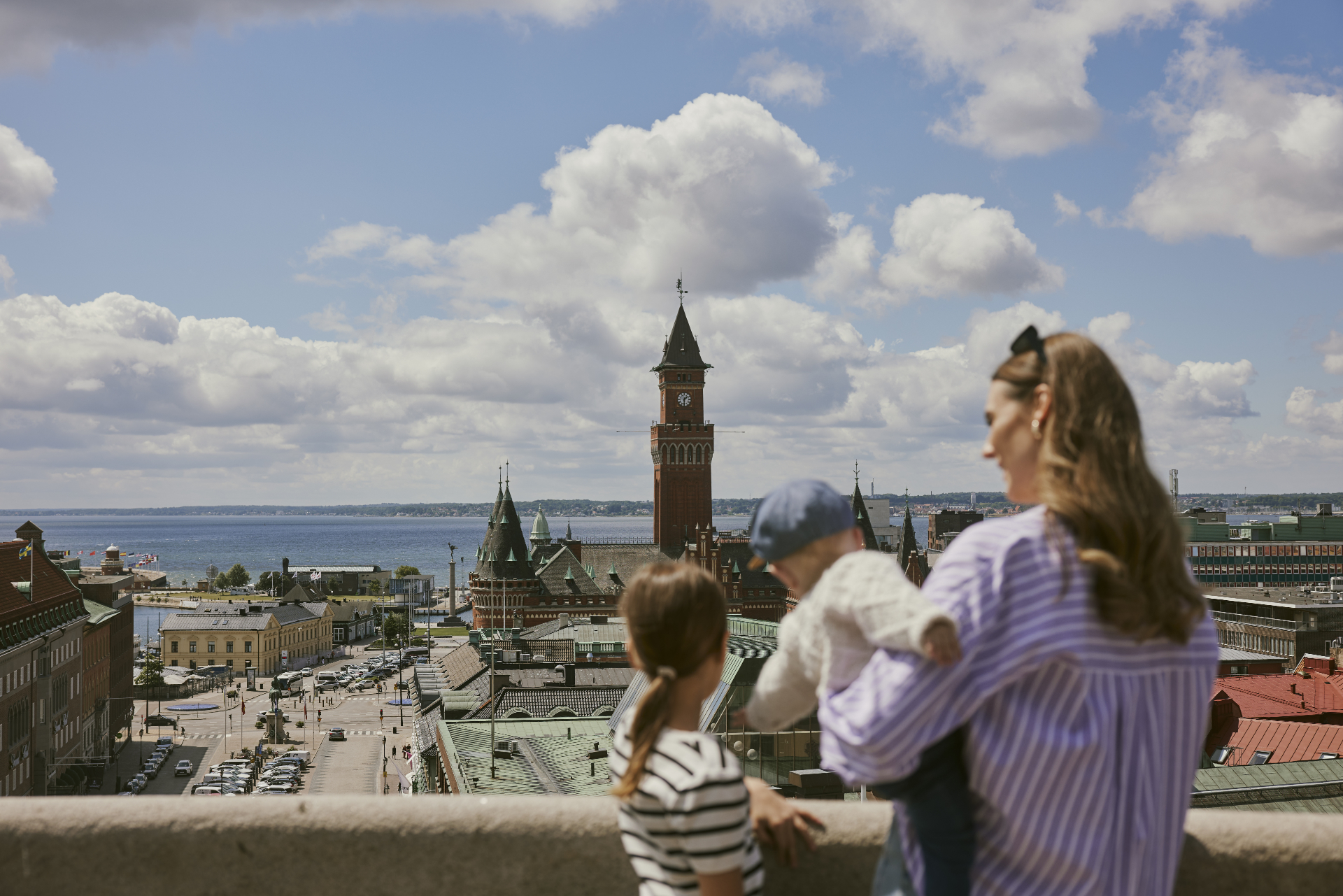 En kvinna och två barn tittar ut över Stortorget och Rådhuset från Terrasstrappornas topp