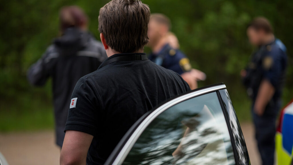 En miljöinspektör i förgrunden och poliser i bakgrunden.