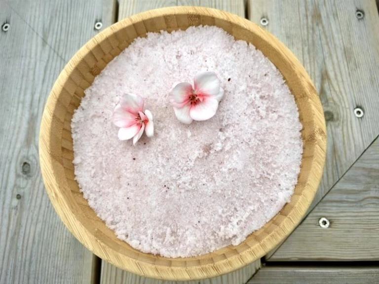 Lätt rosa rengörande saltskrubb i en träskål.