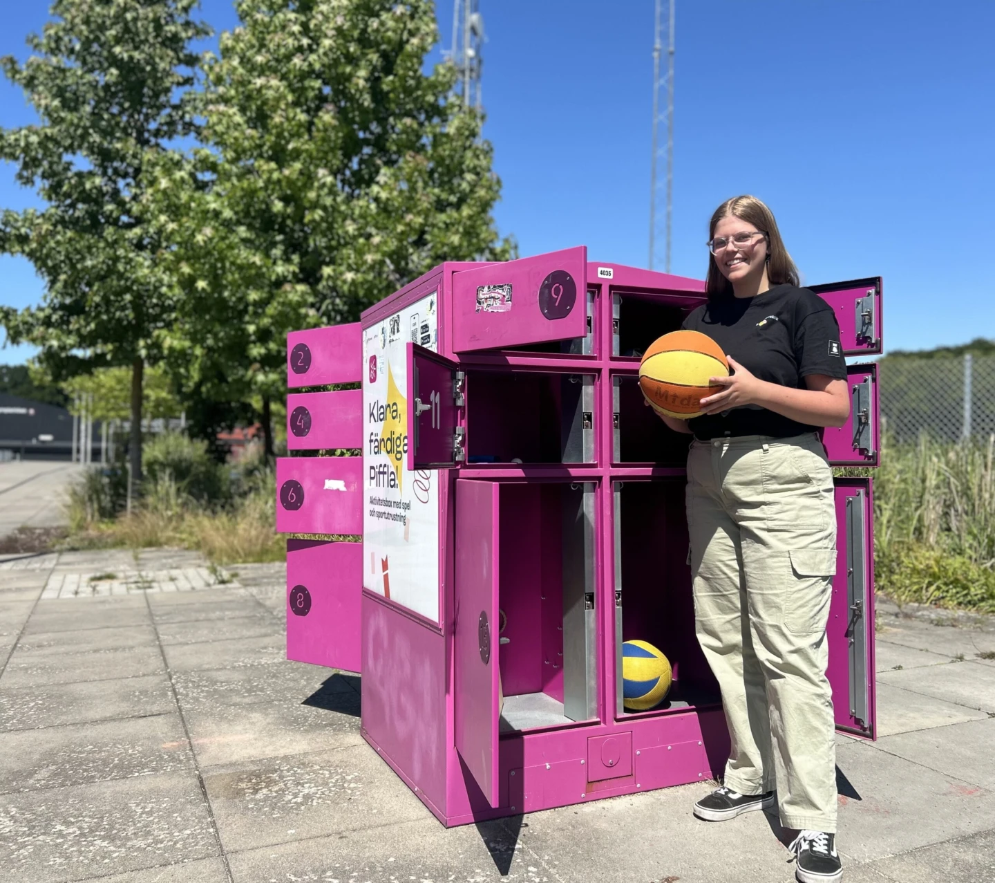Tjej som står vid Piffl aktivitetbox och håller en baskedboll