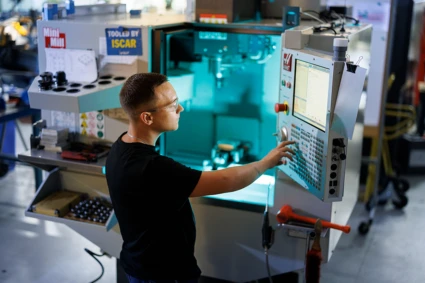 en person står framför en stor instrumentbräda i en fabrik. Personen ser koncentrerad ut.