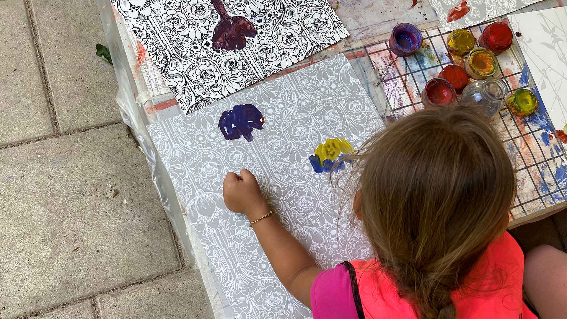 Foto på barn som målar utomhus vid ett lågt bord på Adolfina förskola.