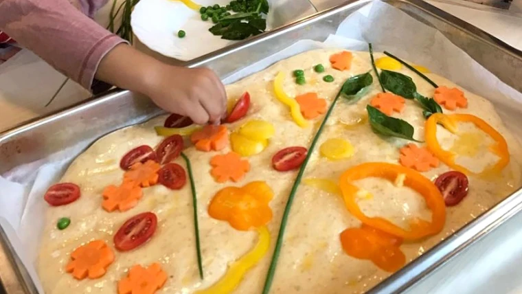 Foto på barn som dekorerar en deg i en form på Lussebäckens förskola.