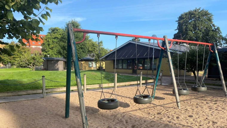 Husensjö förskola, vy från gården med gungor i förgrunden.