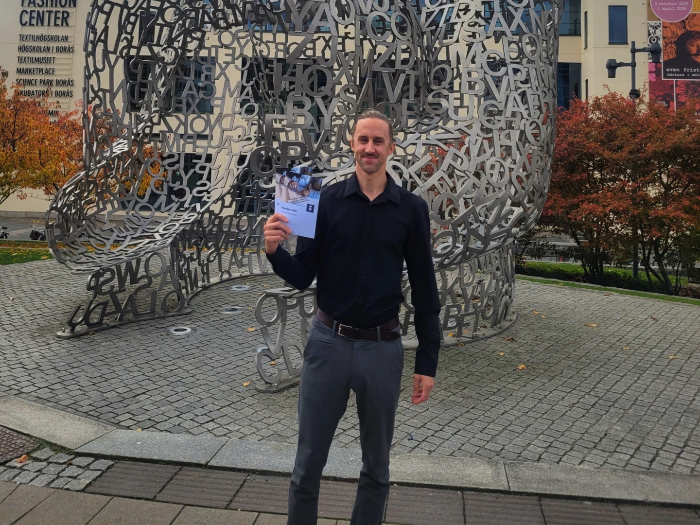 En man står framför ett konstverk och håller en broschyr i handen.