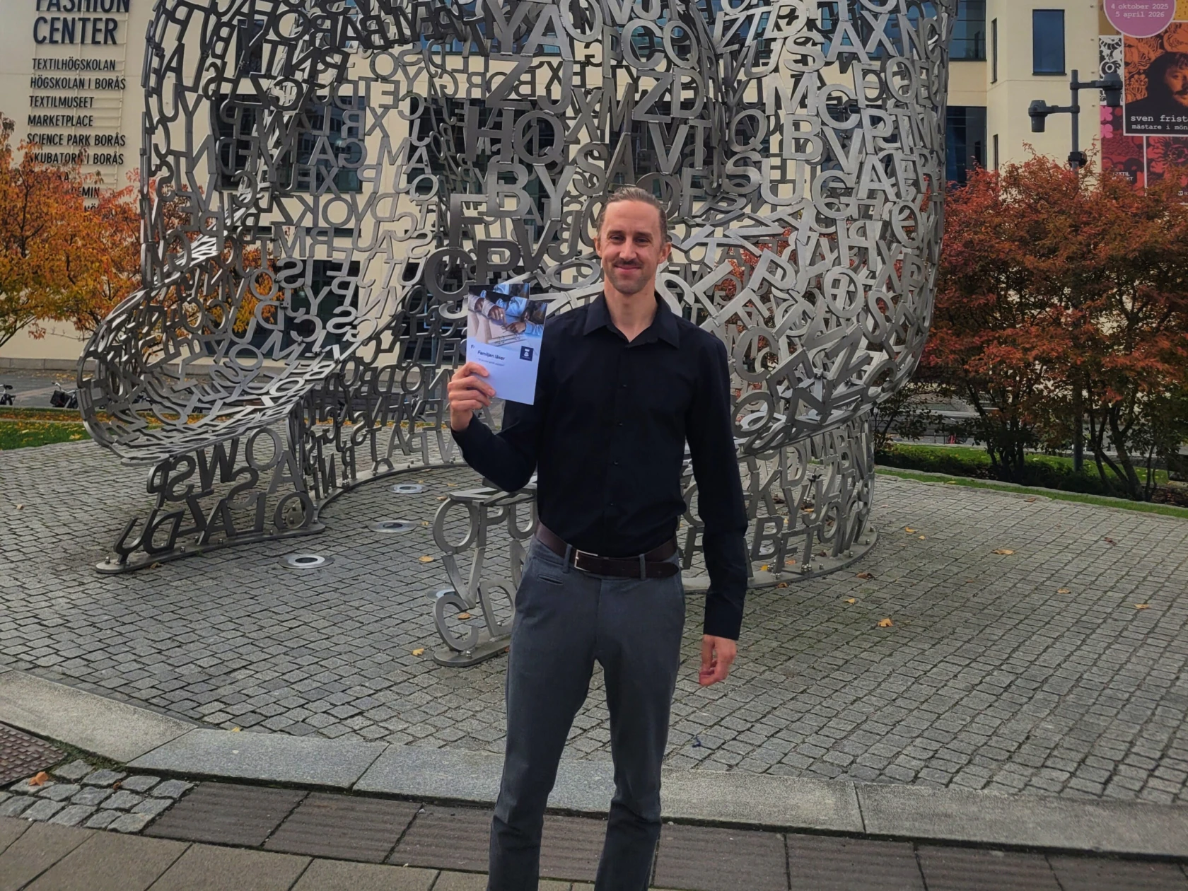 En man står framför ett konstverk och håller en broschyr i handen.