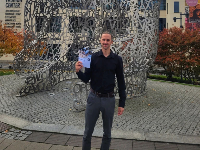 En man står framför ett konstverk och håller en broschyr i handen.