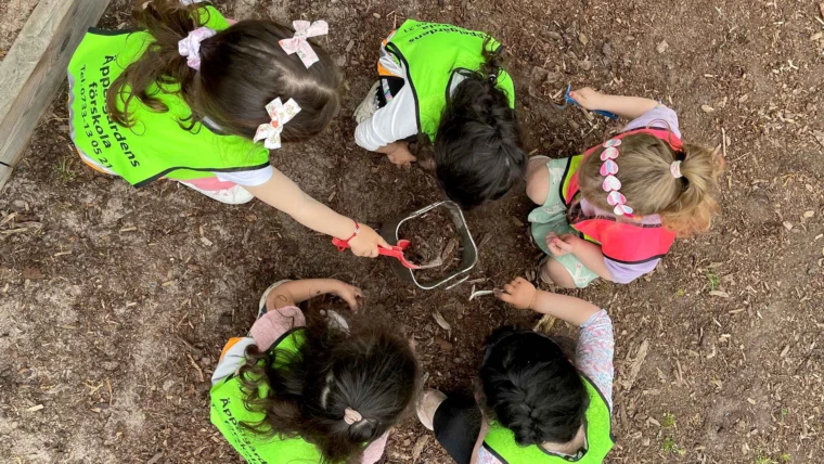 Foto på barn undersöker jorden utomhus på Äppelgårdens förskola.