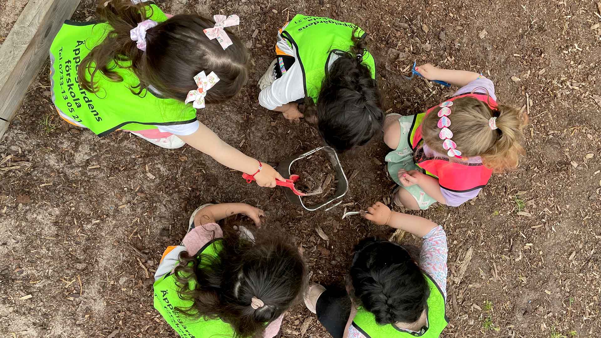 Foto på barn undersöker jorden utomhus på Äppelgårdens förskola.