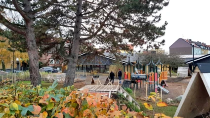 Foto på Stattena förskola med vy mot gården med lekmaterial och nivåskillnader för äldre barn.