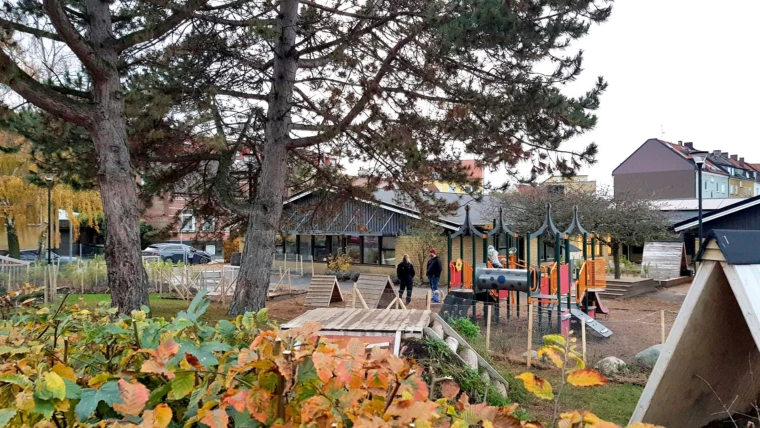 Foto på Stattena förskola med vy mot gården med lekmaterial och nivåskillnader för äldre barn.