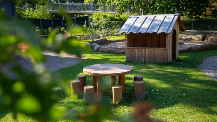 Dalhems förskola, del av gården med sittplatser och lekstuga i naturmaterial. Foto: ChHo SFF 2024